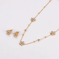 Nahaufnahme von goldenem Edelstahl-Schmuckset mit Kristallblumen-Anhänger und Ohrsteckern - Gold