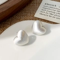 Macro di orecchini a cuore in argento spazzolato su un vassoio di ceramica bianca - Cuore Spazzolato / Argento