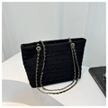 Close-up of black tweed tote bag featuring gold chain straps on a minimalist background - Black
