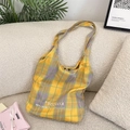 Détail du sac cabas en toile à carreaux jaune et violet sur un canapé crème - Grille jaune et violette