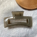 Detail view of a large translucent grey rectangular hair claw clip with a hollow design - Jelly Grey