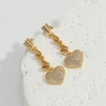 Vista de detalle de pendientes de corazón dorados con circonitas sobre fondo blanco - Pendiente Largo / Corazón de Circonita Blanca