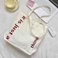 Dettaglio borsa shopper in tela crema con scritta accanto a un computer portatile - Beige Con Lacci