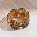 Detail van luipaardhars en goudkleurige metalen armband op een vintage boekbasis - Armband - Lichtkoffie