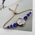 Close-up of golden bracelet watch with blue heart-shaped stones and pearl dial - Rose Gold Blue