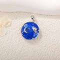 Detailed view of blue circular moon and star locket with silver frame on sand - Silver Moon