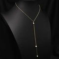 Elegant gold Y-shaped necklace with white freshwater pearls on a black display stand - Simple Pearl Pendant Necklace