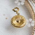 Golden round pendant with sunburst texture and zircon center on lace background - Zircon Sunburst Medallion