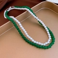 Detail of layered green beaded necklace and white pearl choker on a golden tray - Pearl Layered/Green Round Beads