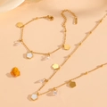 Detalle de un conjunto de joyas de trébol en acero inoxidable dorado sobre seda fina - Conjunto De Concha Blanca Dorada (C518-C519)