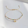 Detail eines verstellbaren Boho-Perlenarmbands mit goldenem Buchstaben-L-Anhänger und Kordel - Buchstabe L
