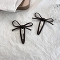 Détail de deux pinces à cheveux papillon en cuir marron foncé sur fond blanc épuré - Marron