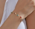 Goldenes Armband mit fünf bunten Herzsteinen, am Handgelenk einer Frau getragen - Armband