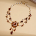 Dettaglio di collana dorata vintage con pendente in cristallo ambra e perle finte - Collana-Caffè