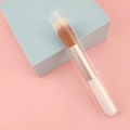 Portable mini blush brush with soft synthetic bristles and white handle on pastel backdrop - White Highlight Brush
