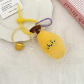 Dettaglio portachiavi a forma di frutto in peluche giallo con moschettone viola su tappeto - Banana
