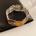 Dettaglio del bracciale smaltato vintage con trama marmo ambra su pelle nera di lusso - Argento-Giallo-Marrone