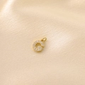 Detailed view of micro-paved zircon letter G pendant on elegant gold satin background - Letter G / Gold