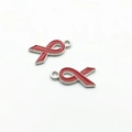 Detailed close-up of two red enamel ribbon charms with silver edges for DIY jewelry making - Red