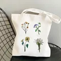 White canvas tote bag featuring minimalist wildflower garden prints on a metal chair - C5 Sunflower and Daisies