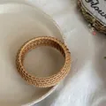 Handcrafted woven rattan bangle in natural wood color displayed on a ceramic plate - Large (Woven) / Brown