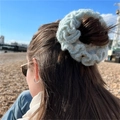 Handmade crochet ruffle scrunchie in light green yarn worn on a hair bun outdoors - White with Blue Edge