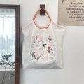 Detail of embroidered tote bag with tulip patterns and woven rope handles on a hook - Smiley Flower White