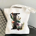 Detail view of white canvas tote bag with floral letter L print on a black chair - Letter L / 35*40cm
