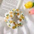 Chiffon scrunchie with lemon fruit pattern on white fabric over an open book - White Orange Fruit