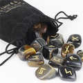 Blue tiger eye rune stones set with gold engravings spilling from a black velvet pouch - Blue Tiger Eye