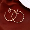 Dettaglio di orecchini geometrici dorati con trama diamantata su seta rossa elegante - Orecchini a clip / Oro