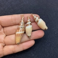 Three natural conch shell pendants with gold plating shown on hand in various sizes - No.12 (Various Sized Conchs - Gold Edge)