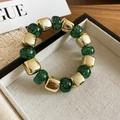 Detailed shot of green acrylic beads with glitter and square gold metal beads on a bracelet - Green