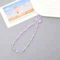 Gros plan du bijou de téléphone avec nœud rose, perles en cœur et perles irisées sur plateau - Violet