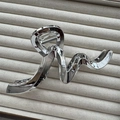 Close-up of a wavy silver metallic hair claw clip on a beige textured display surface - Irregular Silver 13cm