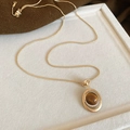 Détail macro du collier pendentif œil de tigre plaqué or sur un présentoir beige - Style Zircone à Double Halo Ovale (2#项链-金色-咖色)