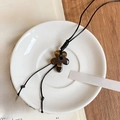 Macro shot of tiger eye flower pendant on a white ceramic plate and vintage book background - Floral Shape Tiger Eye Pendant Style (37# Necklace-Coffee-Tiger Eye Stone)