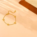 Pulsera de corazón de acero inoxidable dorado con cuatro dijes sobre un fondo texturizado - Pulsera de Corazón (B108) / Dorado