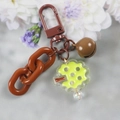 Close-up of brown plastic chain link keychain with metal bell and patterned charm - 5126-9 Brown Cartoon