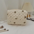 Vista dettagliata della borsa trapuntata beige con ricamo a orso e nastro decorativo - Pochette beige