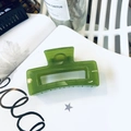 Close-up of emerald green rectangular hair claw clip with transparent finish on paper - Turquoise Green