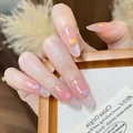Detail of nude pink gradient press-on nails with heart pattern on a model's hand - By2197 Almond Face And Peach Cheeks / Glue Type