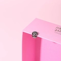 Detail of pink gift box with round metal magnetic clasp and decorative typography - Electroplated Gun Black