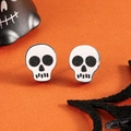 Makroaufnahme von weißen Totenkopf-Ohrsteckern mit schwarzen Augen für Halloween-Kostüme - Schädel