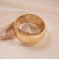 Close-up of wide polished gold metal cuff bracelet on natural stone with warm lighting - Gold Round Medium