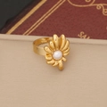Makroaufnahme eines goldenen Blumenrings mit Perlenakzent auf einer beigen Oberfläche - Ring
