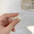 Elegant s925 silver irregular hammered golden hoop earrings held to show size - Versatile Simple Hoop Earrings - A554 Gold