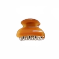 Macro detail of a small amber resin hair claw clip with polished finish and silver metal teeth - Orange Yellow