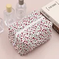 Close-up of floral quilted cotton makeup bag with red flowers and white zipper detail - Red