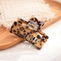Macro detail of tortoiseshell acetate hair claw clip showing glossy finish and spring mechanism - Tortoise
